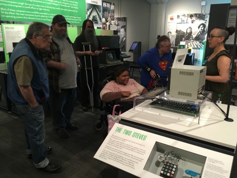 A group of volunteers stands infront of the museum guide as she explains how a very old looking computer works inside the Living Computer Museum.