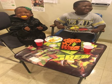 Two young children sit at the kids table at the STAR Open House Event right outside of the STAR center. They are enjoying vegetable snacks.